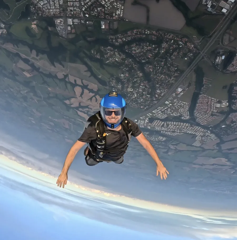 Vitor em queda livre, sorrindo, com capacete azul